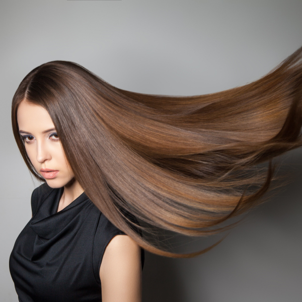 A woman with shiny, healthy hair after professional color correction by a hair color specialist.
